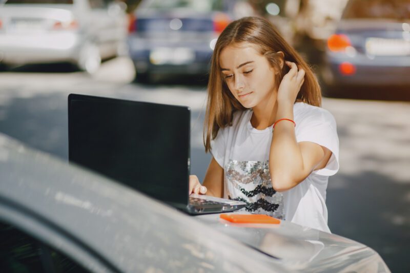 Žmogus naršo automobilius internetinėje platformoje naudodamas nešiojamąjį kompiuterį.