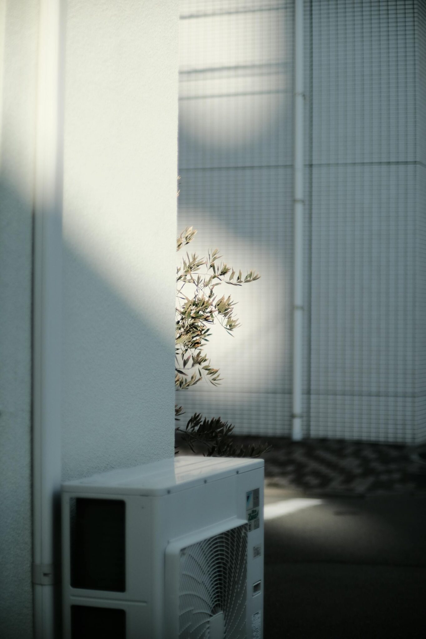 Modernus šilumos siurblio išorinis blokas sumontuotas prie šiuolaikiško namo fasado.